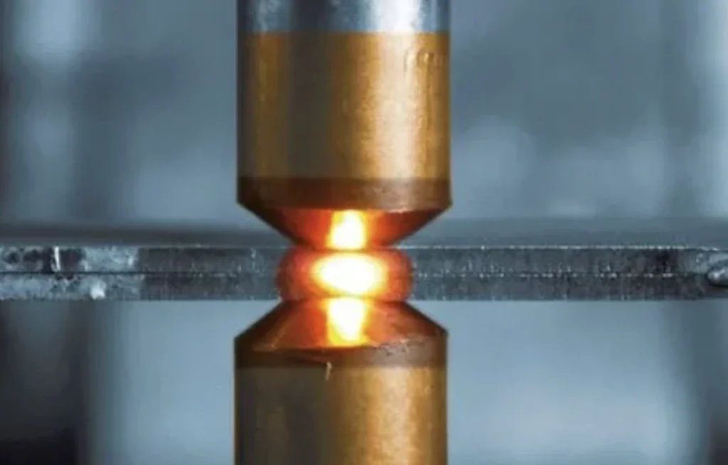 Close-up of aluminum spot welding process with intense heat between metal sheets